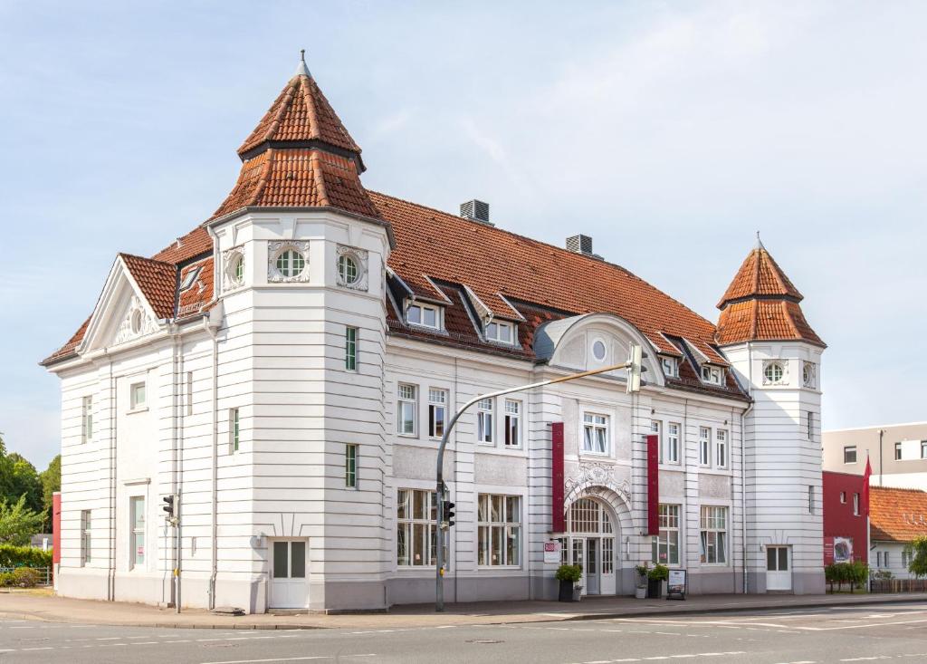 石勒苏益格阿尔特克雷斯班霍夫酒店的一座白色的大建筑,有红色的屋顶