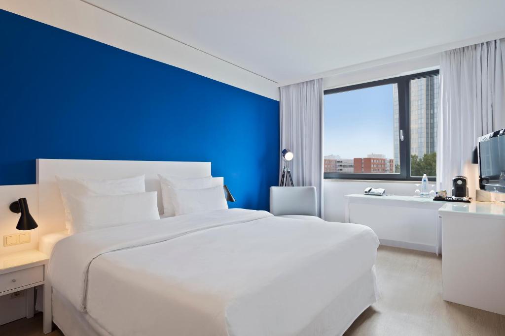 美因河畔法兰克福Hotel Frankfurt Messe Affiliated by Meliá的卧室配有白色的床和蓝色的墙壁