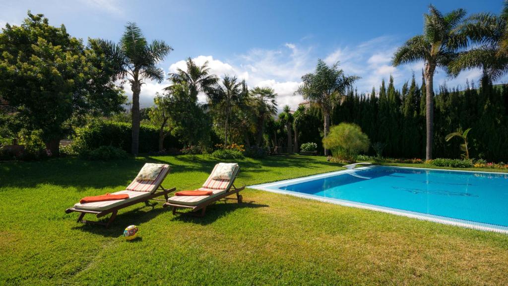 拉奥罗塔瓦Lujoso apartamento en Finca Robles 2的两把椅子坐在游泳池旁的草地上