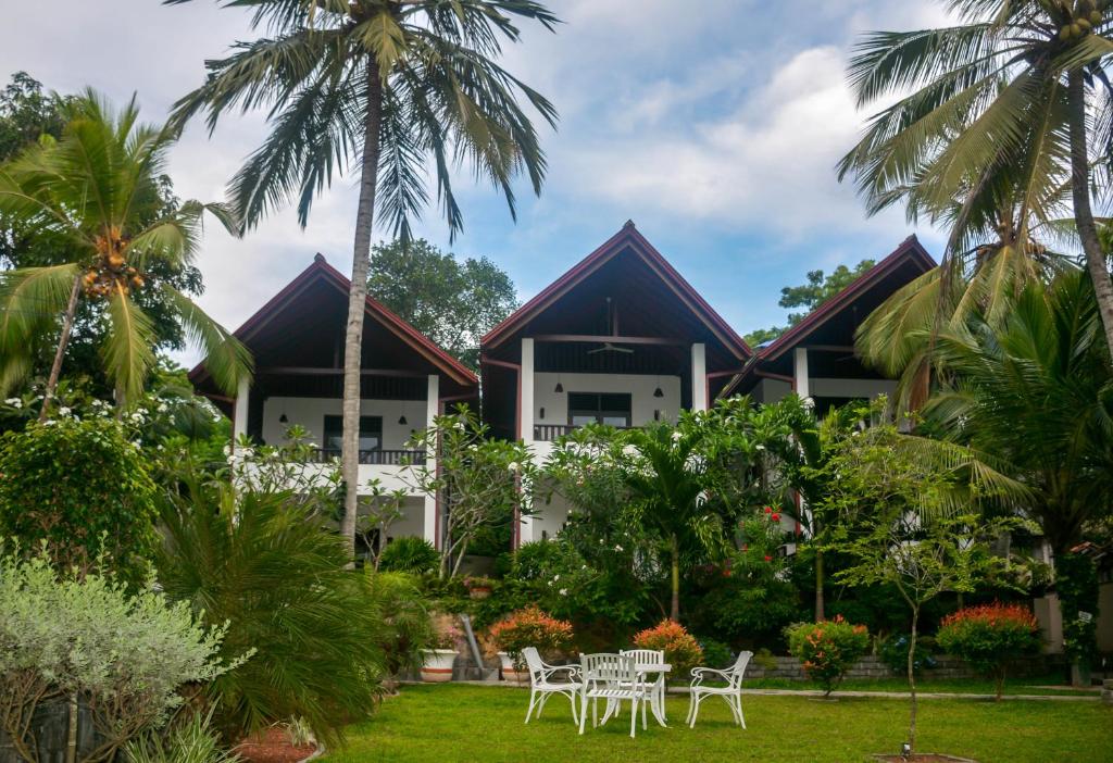 坦加拉Goyambokka Guesthouse的前面有椅子和棕榈树的度假胜地