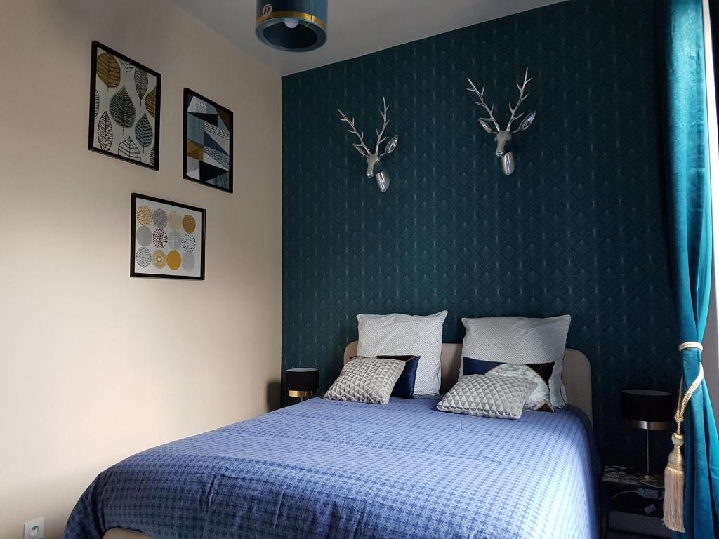沙托鲁Le Prestige Saint André的卧室配有一张蓝色床,墙上挂着鹿头