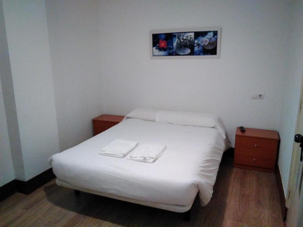维戈黄金锚旅馆的小房间设有一张白色的床,墙上挂着一张照片