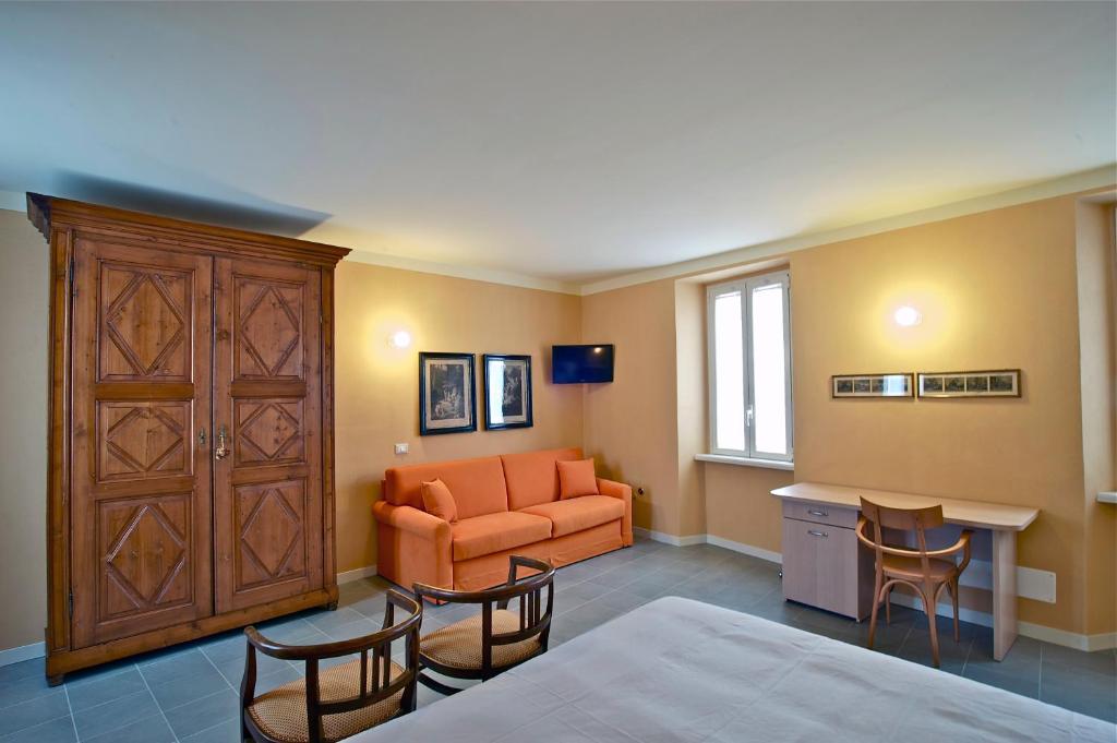 贝拉吉奥Locanda della Maria的一间卧室配有橙色的沙发、桌子和椅子