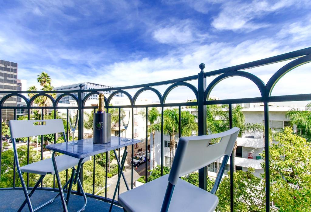 洛杉矶Beverly Hills Adjacent 2-Bedroom Penthouse的阳台配有蓝色的桌子和白色的椅子。