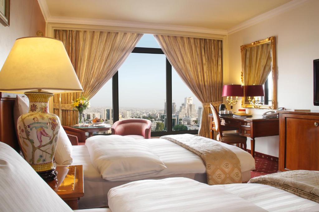 安曼安曼摄政宫酒店的酒店客房设有四张床、书桌和窗户。
