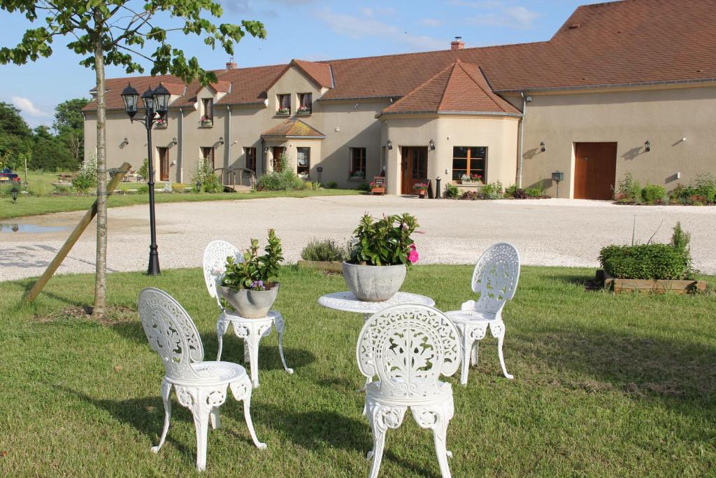Brugny-VaudancourtLe Manoir des Arômes的院子里的一组白色椅子和一张桌子