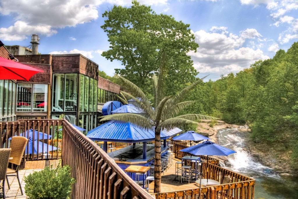 威克斯巴勒The Woodlands Inn的阳台配有桌子和蓝色遮阳伞,享有河流美景。