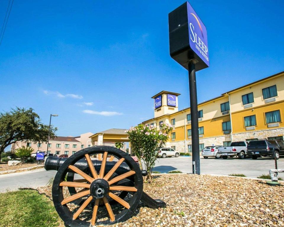 GonzalesSleep Inn & Suites near Palmetto State Park的建筑物前的标志和旧车轮