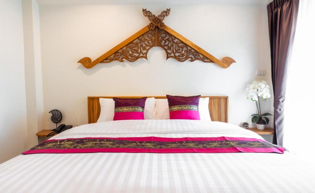 清迈Anumat Premium Budget Hotel的卧室配有一张带粉红色枕头的大床