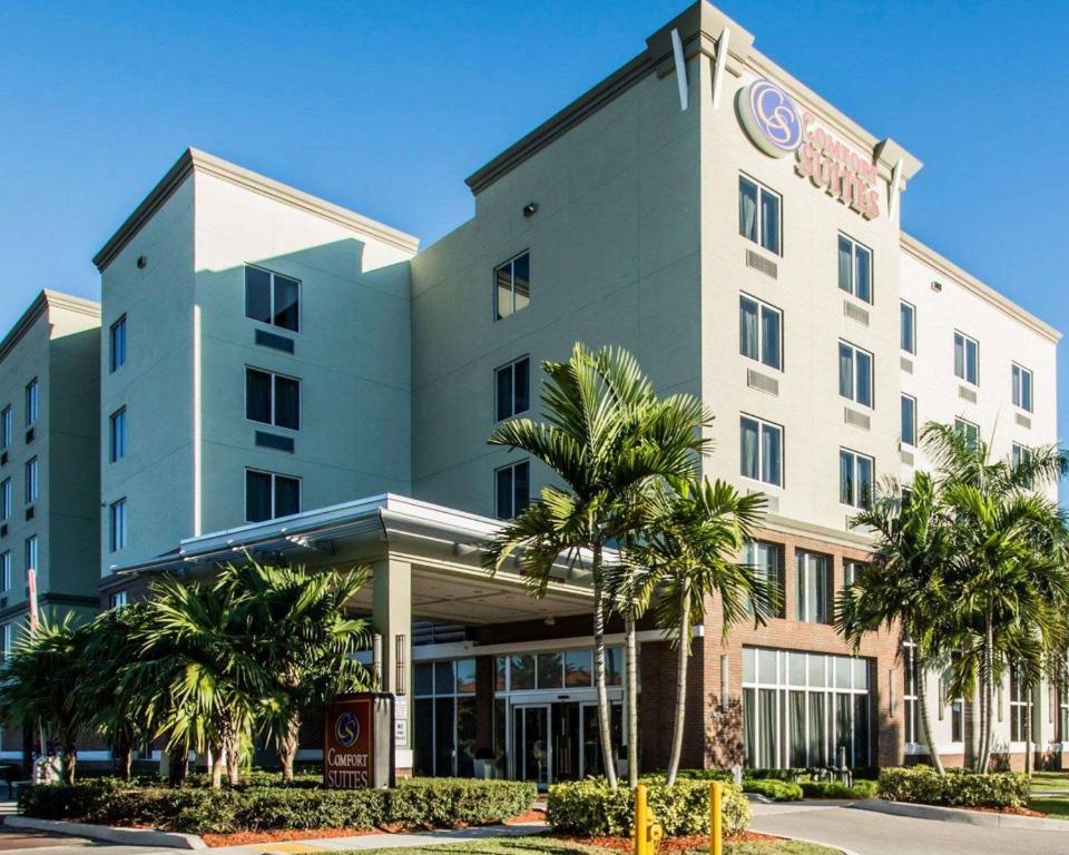 迈阿密迈阿密机场北舒适套房酒店的一座酒店大楼前面有棕榈树