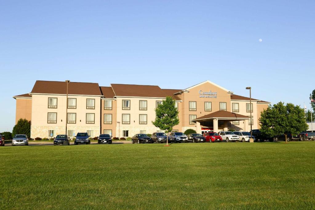 GrinnellComfort Inn & Suites Grinnell near I-80的停车场内停放汽车的大型建筑