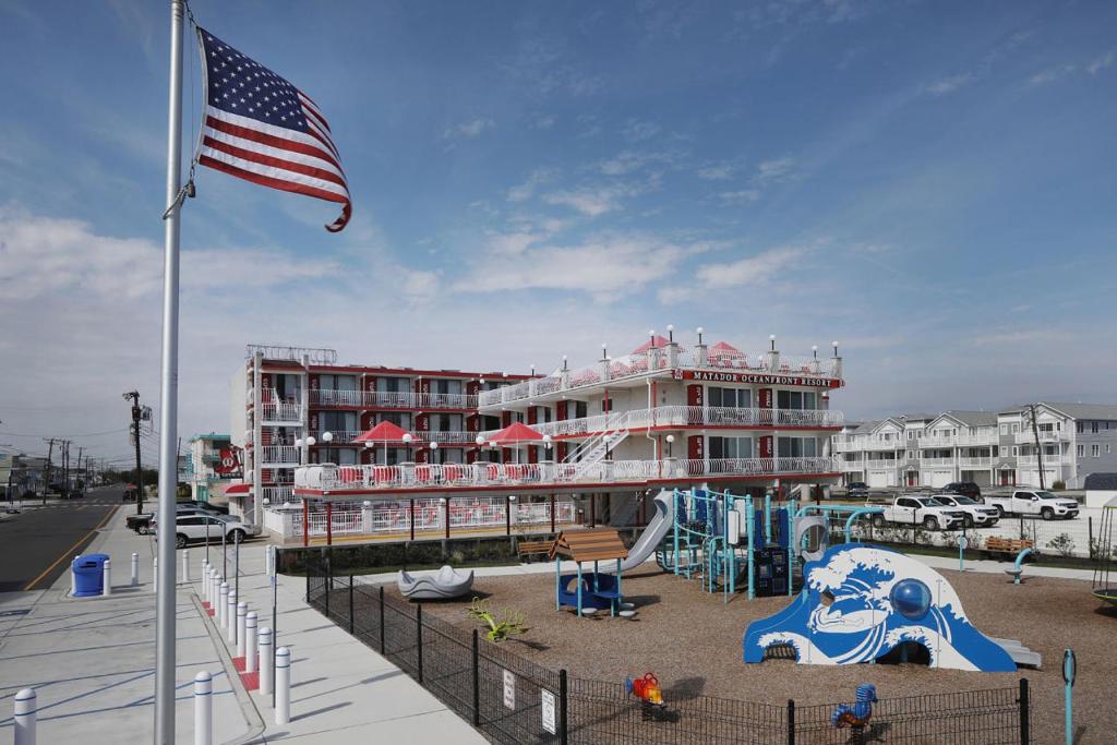 北怀尔德伍德Matador Oceanfront Resort的一座带美国国旗的建筑和一个游乐场