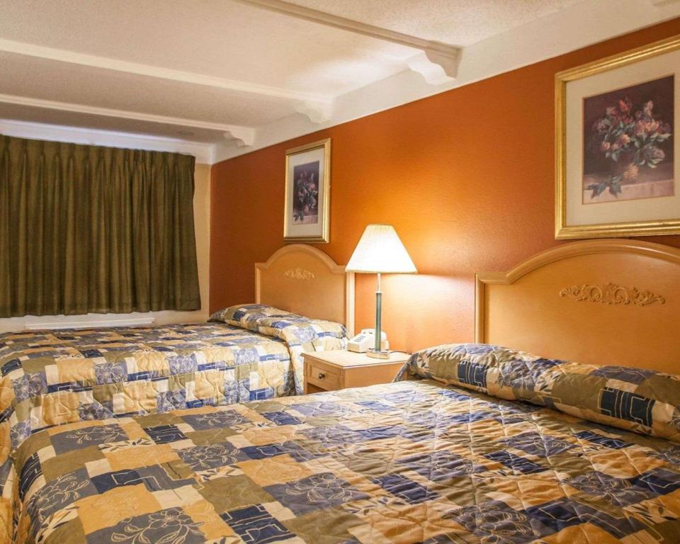 圣查尔斯Relax Inn Saint Charles的橙色墙壁的酒店客房内的两张床
