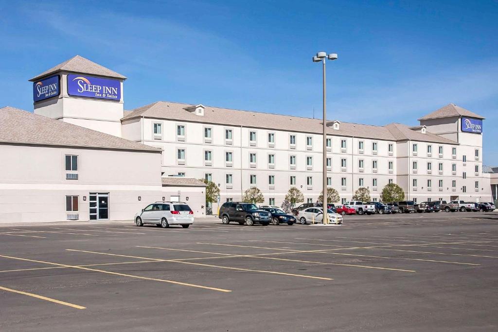 迈诺特Sleep Inn & Suites Conference Center and Water Park的一座白色的大建筑,汽车停在停车场