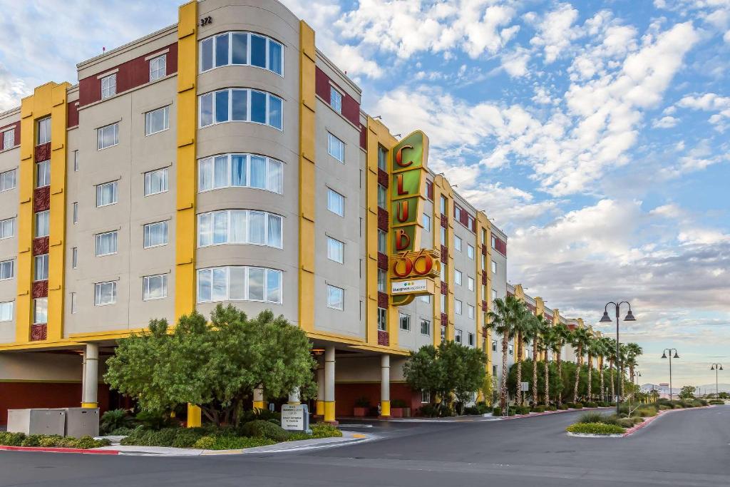 拉斯维加斯蓝绿度假俱乐部36酒店的一条高大的黄色建筑,在街道前方有树木