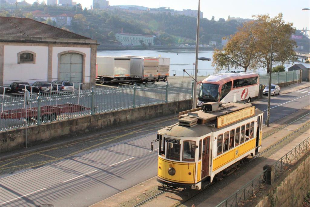 波尔图AlfandegaPorto Apartments的一条黄火车在道路旁的轨道上