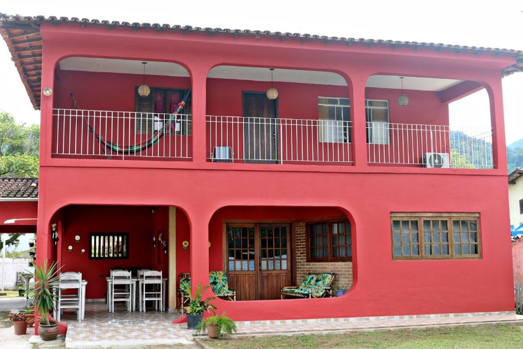 伊利亚贝拉KR Hostel Ilhabela的带阳台和桌椅的红色房屋