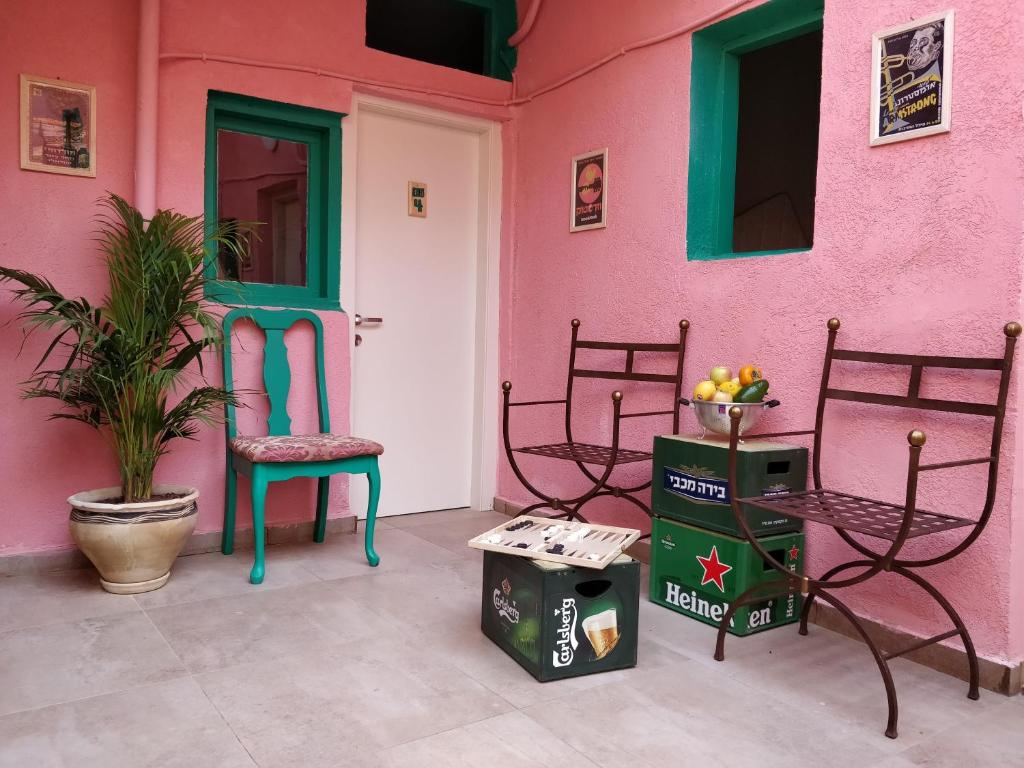 特拉维夫1000Nights Guest House - Near the beach的粉红色的房子,配有椅子和绿门