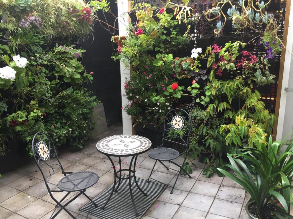 墨尔本Brunswick B & B的庭院配有两把椅子和一张桌子,种有鲜花