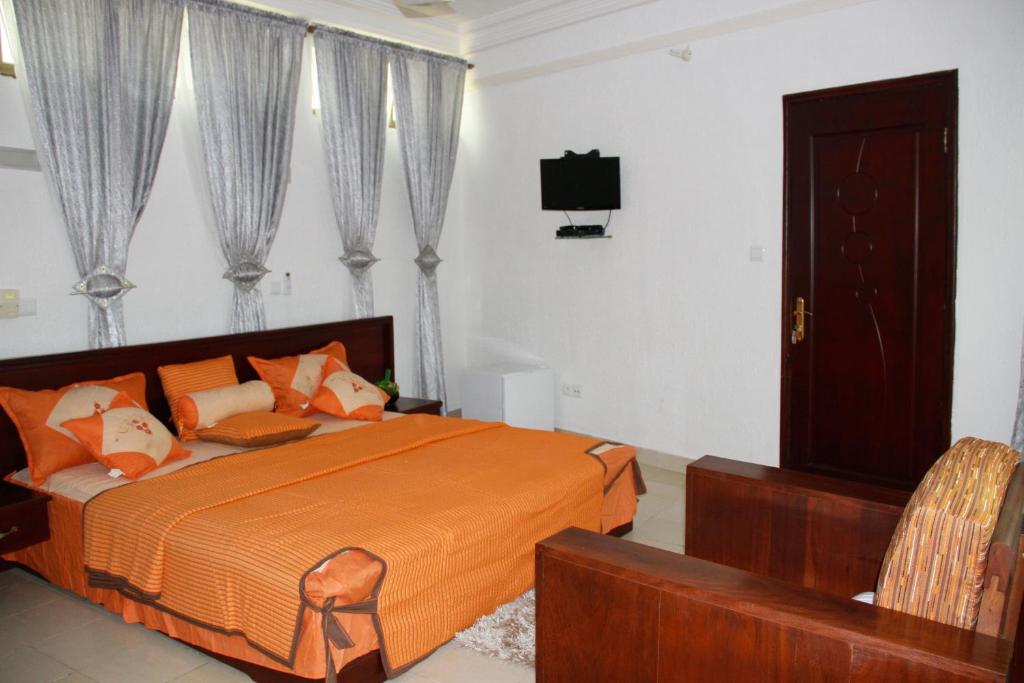 科托努Amazing Grace Residence的一间卧室配有一张床和一台电视