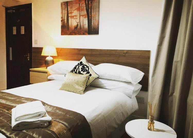 考文垂Bede Apartments的卧室配有一张带白色床单和枕头的大床。