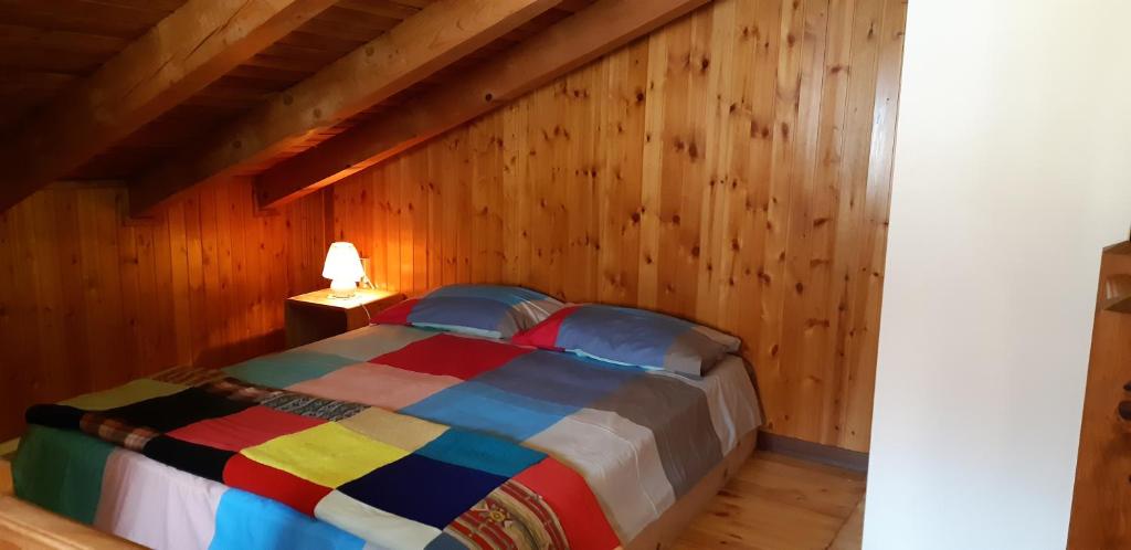 拉马格德莱伊内Casetta di montagna Viuex的木制客房内的卧室配有一张色彩缤纷的床