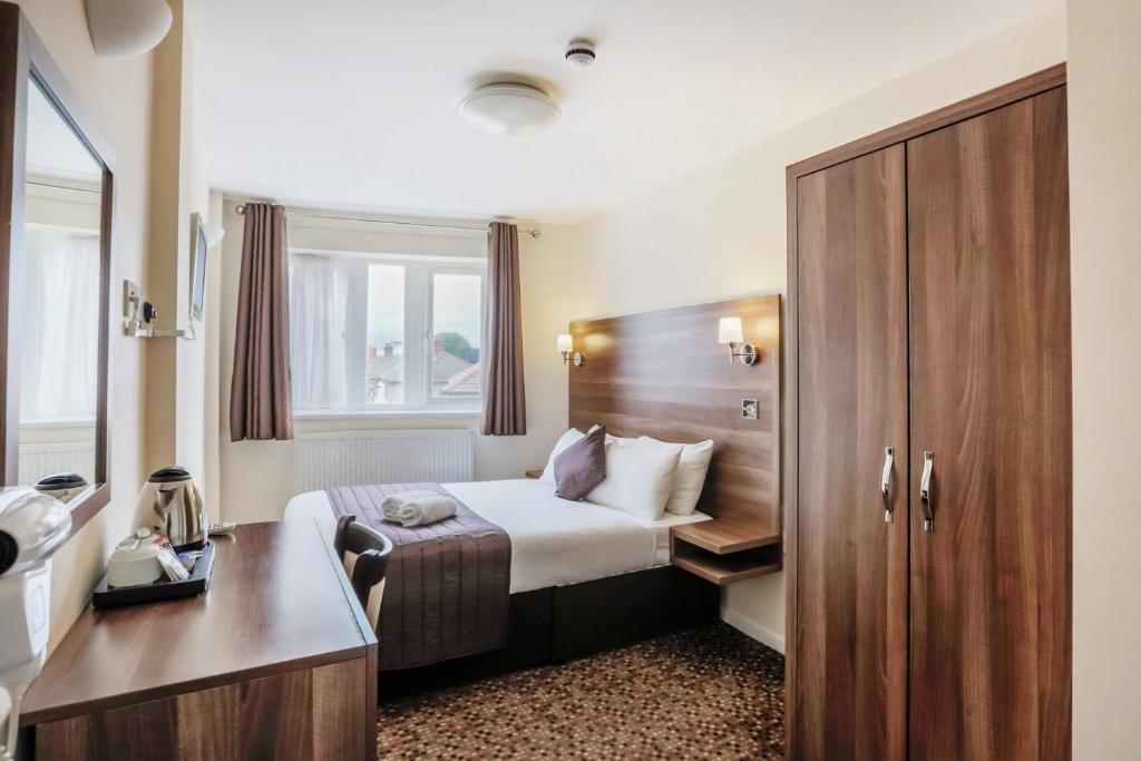 伦敦伦敦埃克塞尔王子摄政酒店的配有一张床和一张书桌的酒店客房