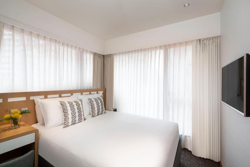 香港香港莎玛港岛北服务式公寓的卧室配有白色的床和电视。