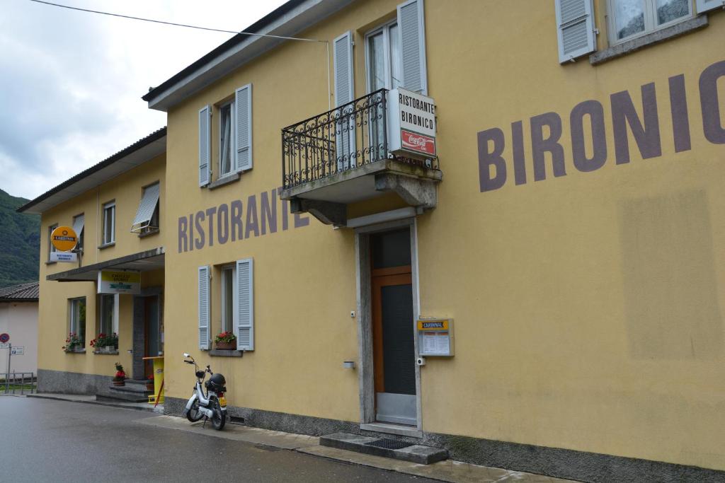 Bironico比荣尼可餐厅及酒店的停在黄色建筑前面的摩托车
