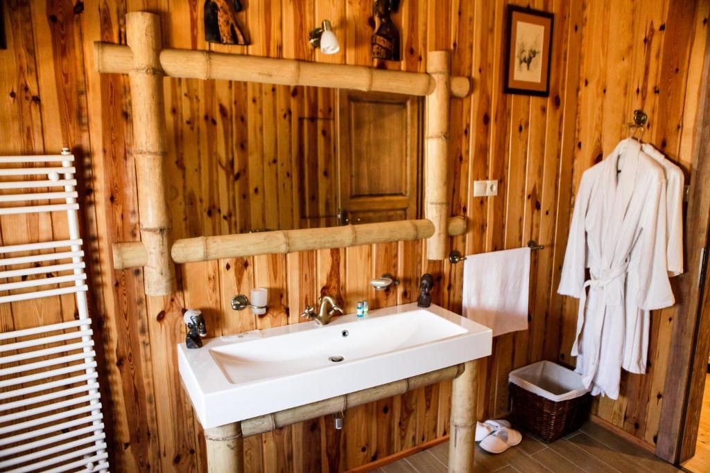 瓦沙罗什瑙梅尼Hunor Hotel és Étterem的一间带白色水槽和木墙的浴室