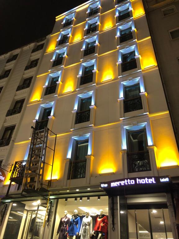 伊斯坦布尔Meretto Hotel LALELİ的一座有灯的建筑,前面有一间商店