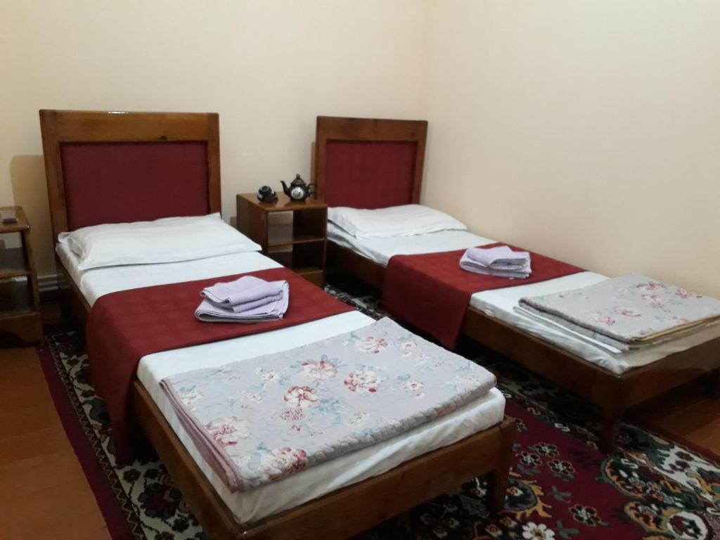 布哈拉Amir-Yaxyo Hotel的红色床单的客房内的三张床