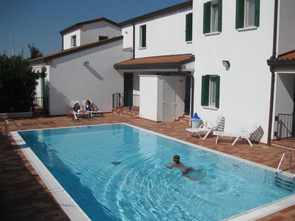 卡奥莱Residence Tamerici的一个人在建筑物旁边的游泳池游泳