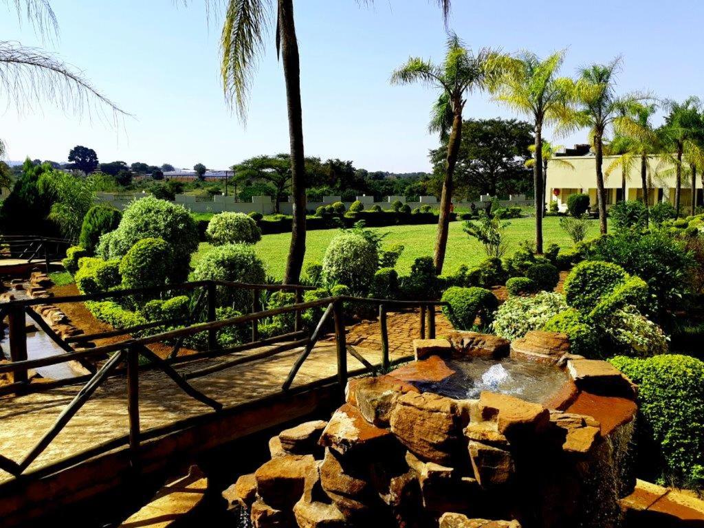 索赫燕杜Naledzi Hotel & Conference centre的花园设有喷泉、棕榈树和灌木