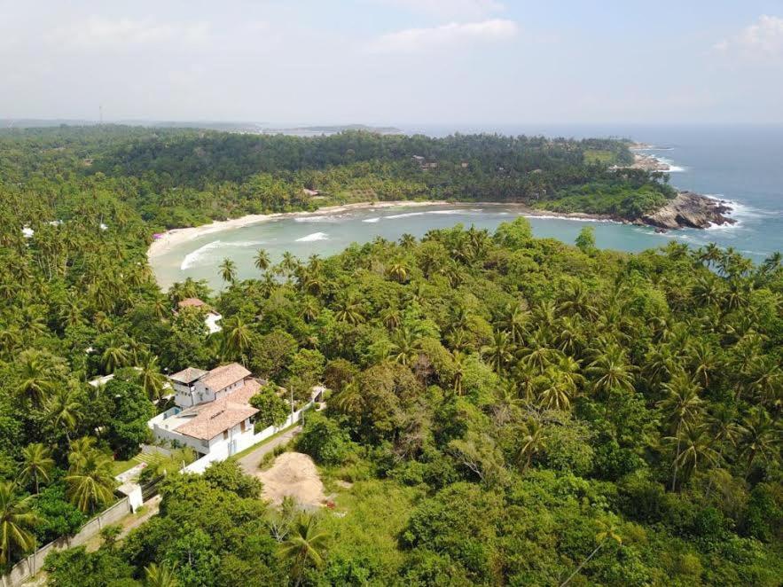 平谷Serene Villa的享有海滩上一座小山上房子的空中景致