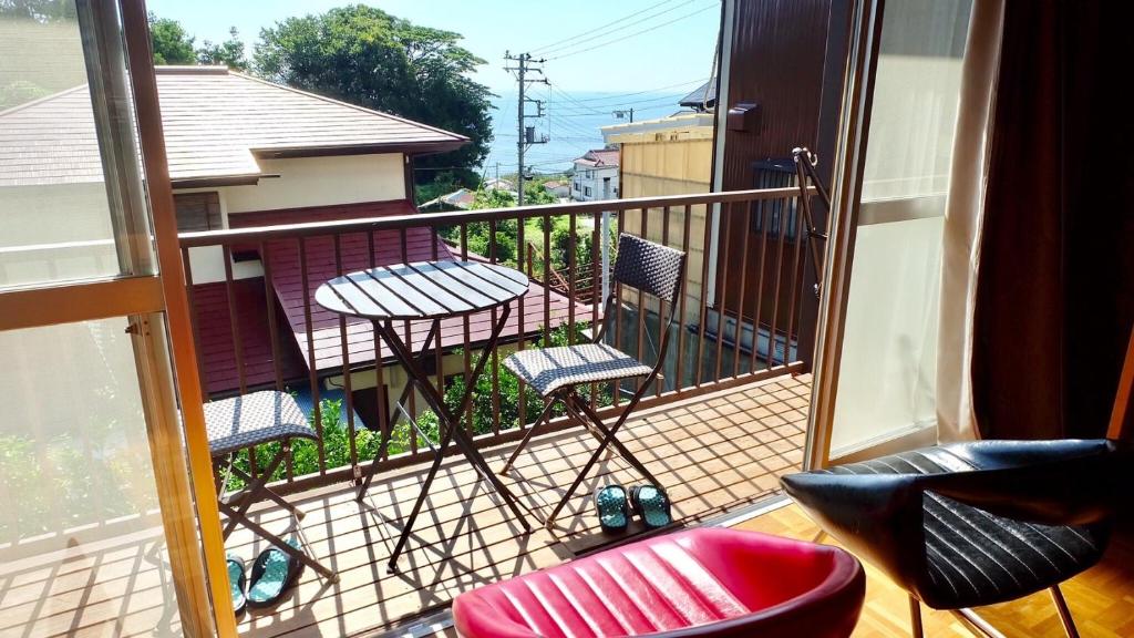 伊东Smart House Oceanview的阳台配有两把椅子和一张桌子,阳台