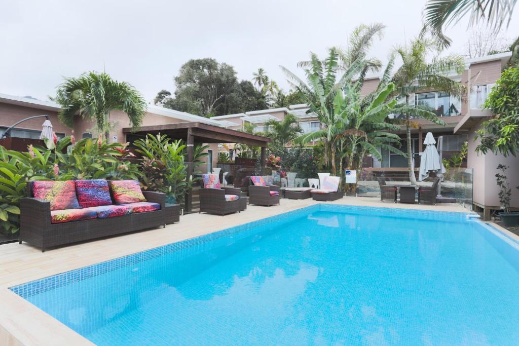 拉罗汤加Kia Orana Villas and Spa的房屋旁的游泳池配有椅子和沙发