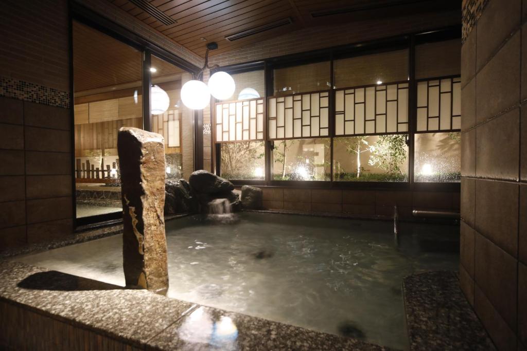 大阪多美迎PREMIUM大阪北滨酒店的带窗户的客房内设有带石柱的浴缸