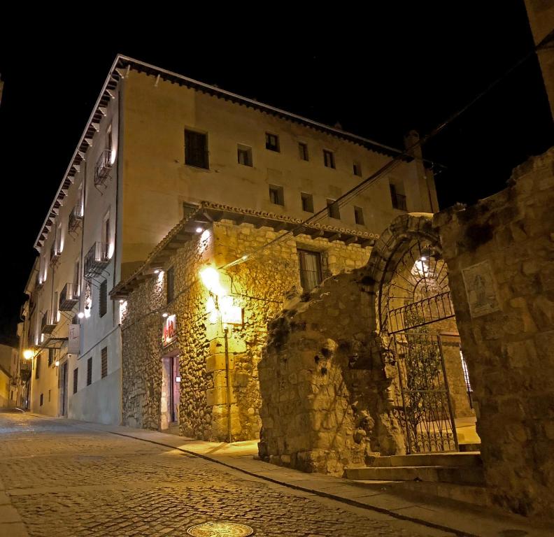 昆卡希拉尔多修道院酒店的街上的一座老石头建筑,晚上有灯