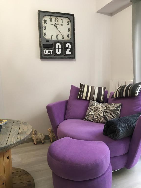拉科鲁尼亚Serendipia的客厅里紫色的沙发,墙上挂着一个钟