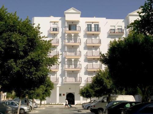 Estepona米格尔安赫尔公寓的一座大型白色建筑,设有阳台,门前设有停车场
