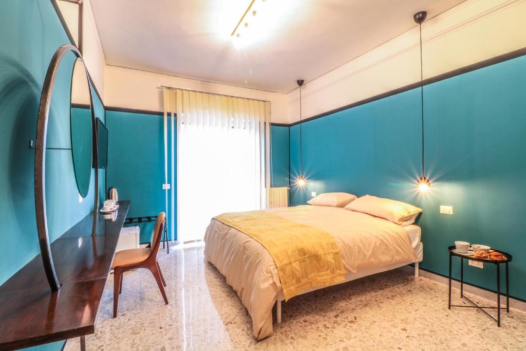 那不勒斯Le stanze di Virgilio的一间卧室设有蓝色的墙壁、一张床和一张书桌