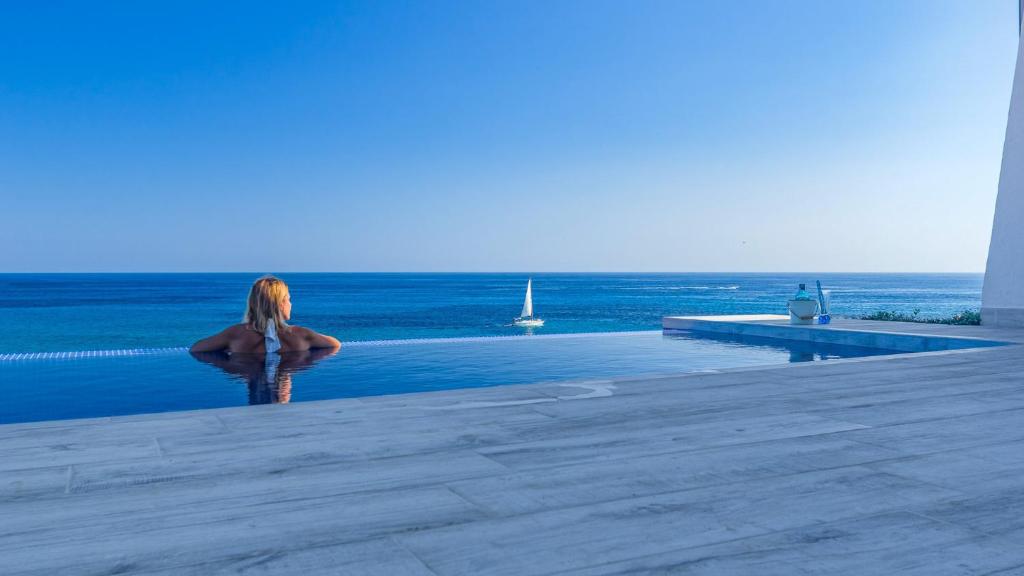 蓬塔普里马Villa Lola的站在俯瞰大海的游泳池旁的女人