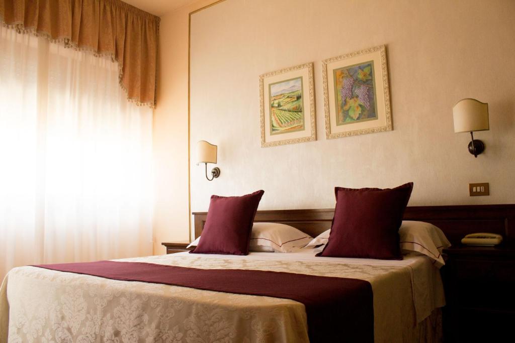 蒙特普齐亚诺Hotel Ristorante Tre Stelle的一间卧室配有一张带红色枕头的大床
