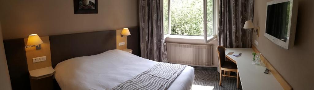 凯泽贝尔古城墙酒店的一间卧室配有一张床、一张书桌和一个窗户。