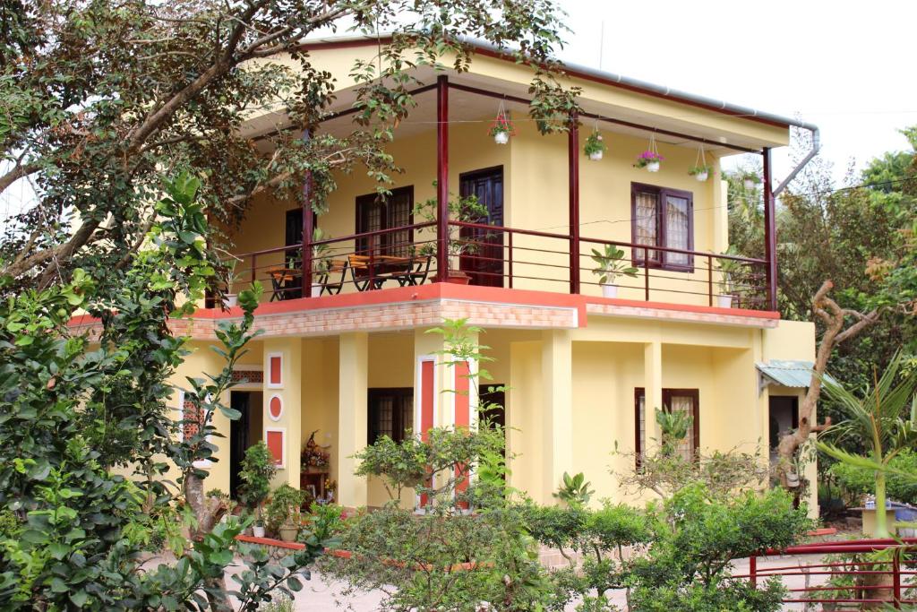 槟知Nguyet Que Homestay & Tours的黄色房子的顶部设有阳台