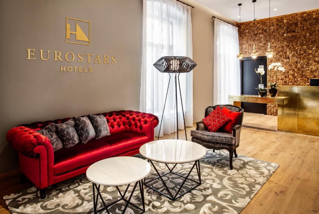 科尔多瓦Eurostars Azahar的客厅配有红色的沙发和两把椅子