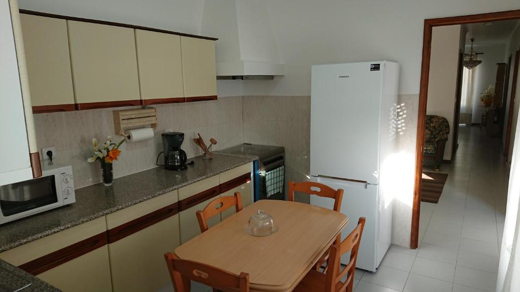 蓬塔德尔加达AL Visconde的厨房配有桌子和白色冰箱。