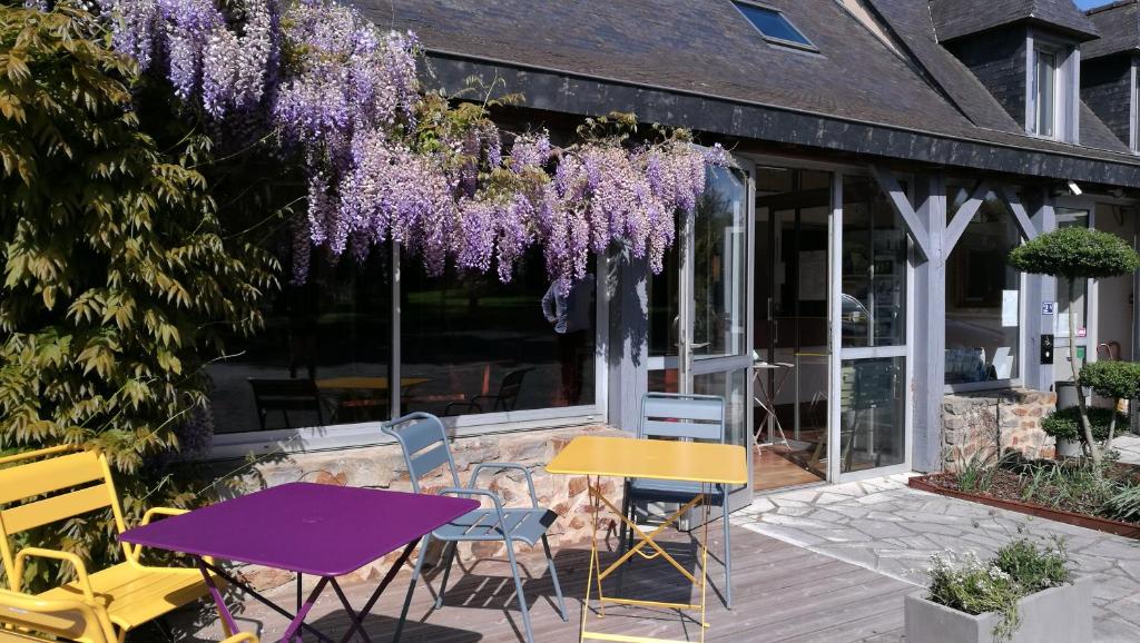 瑟松塞维涅Logis Hôtel Lodge La Valette的庭院里野餐桌椅,紫色紫藤