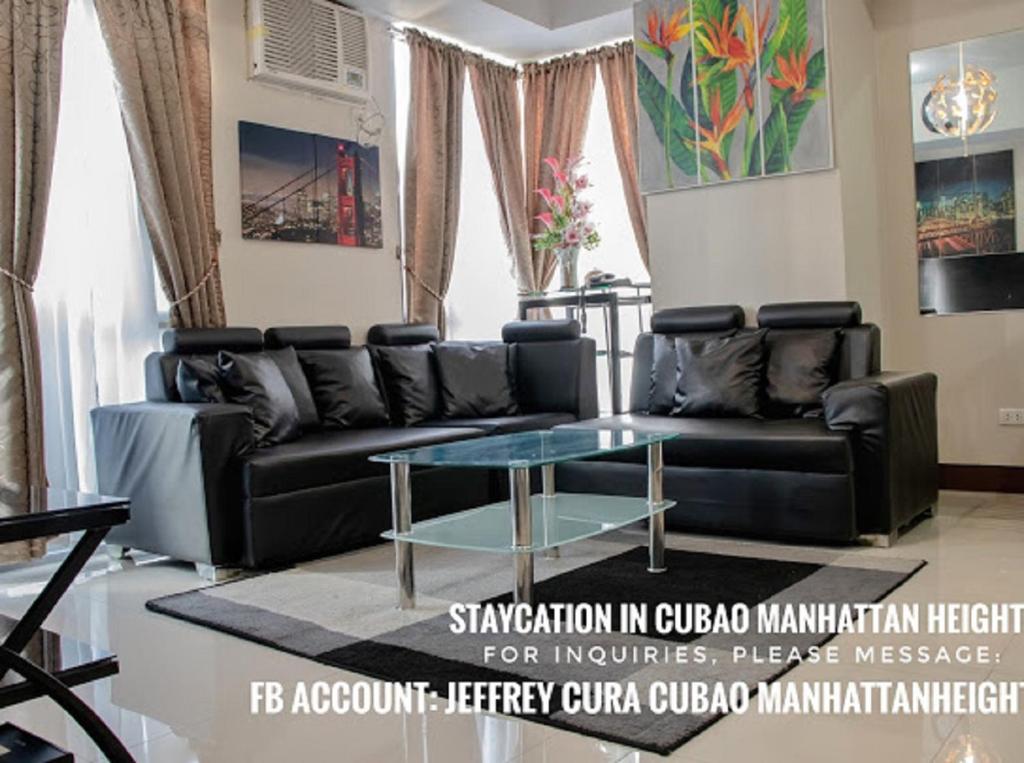 马尼拉5H Tower C Manhattan Heights Cubao QC的客厅配有黑色沙发和玻璃桌